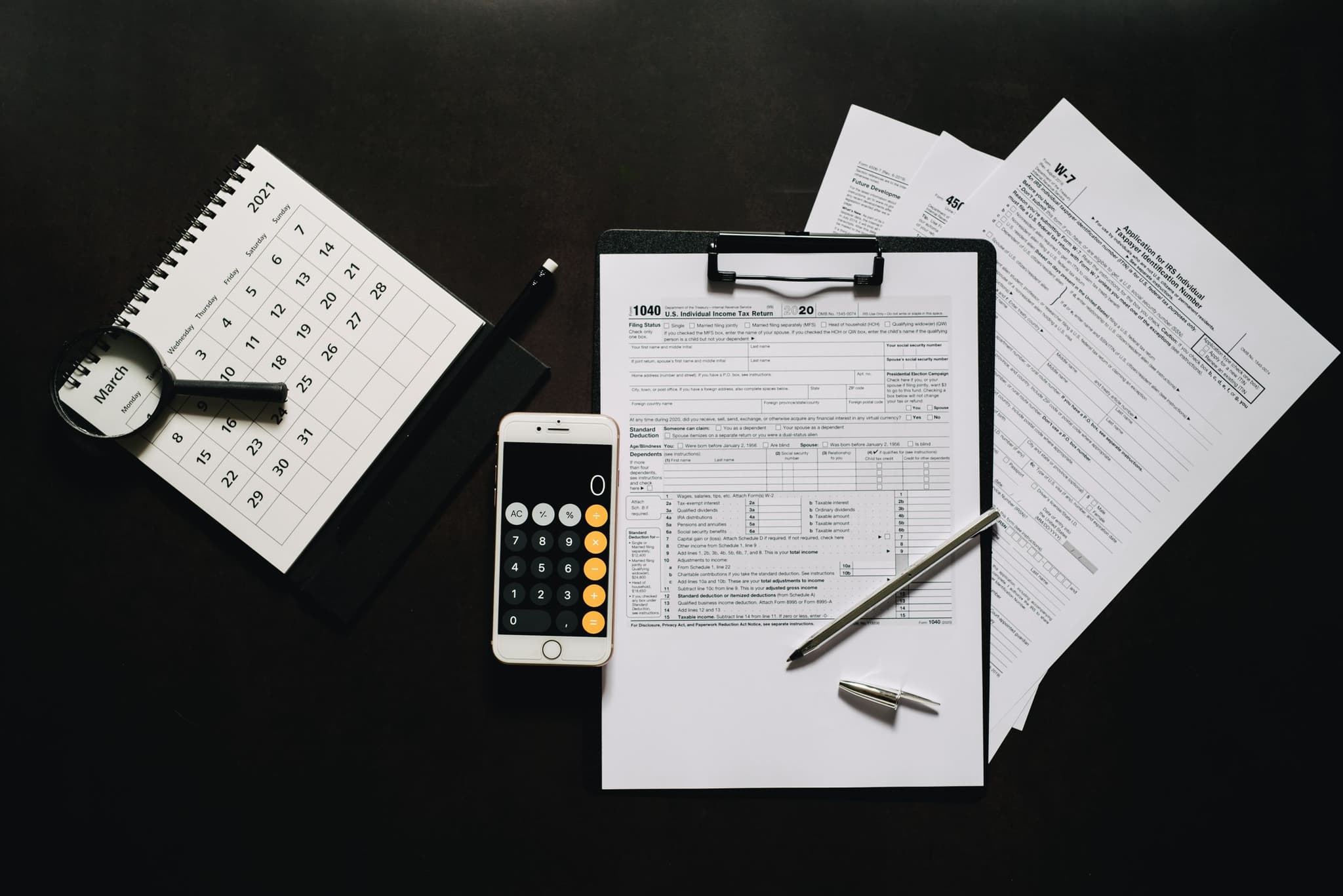 Tax forms, a calculator, and a calendar laid out for an income tax return.